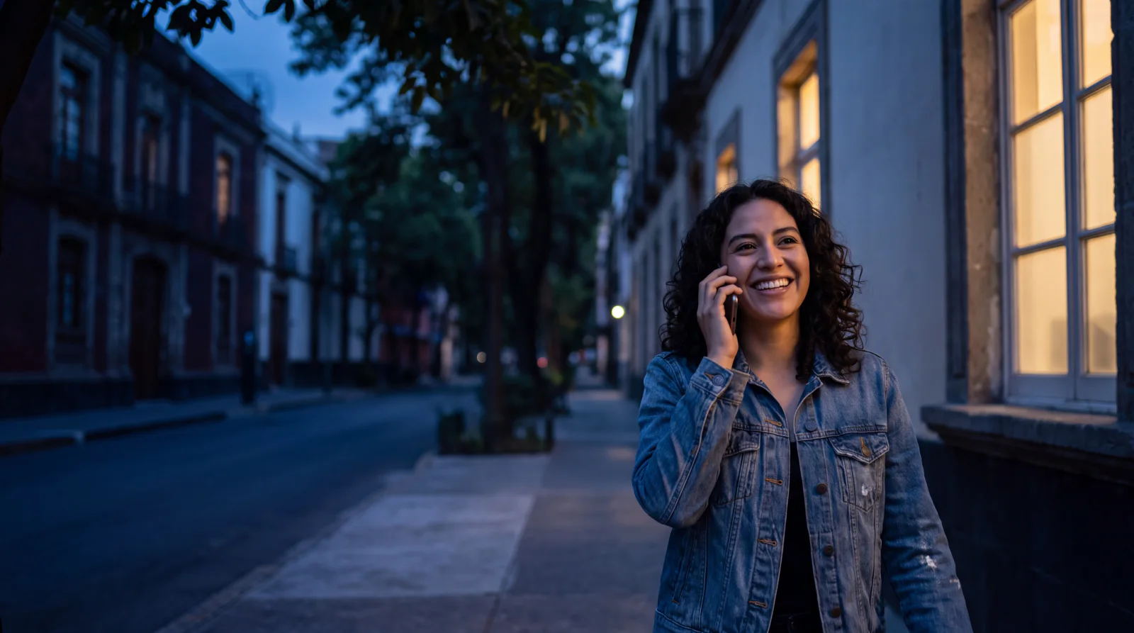 A young woman on a Mexico City street at dusk, talking on her phone