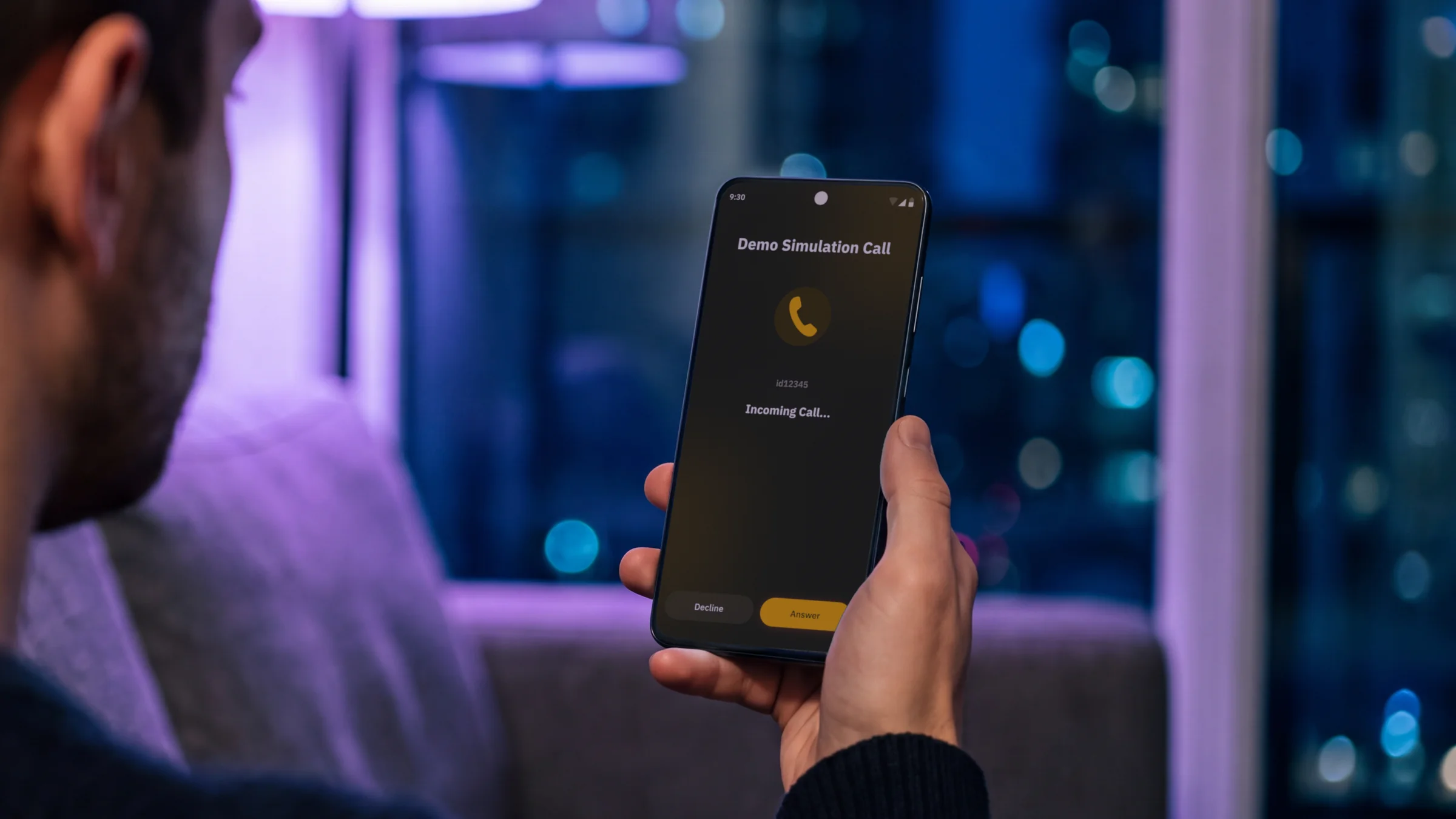 A person on a sofa at night holding an Android phone showing an incoming Jingle demo call